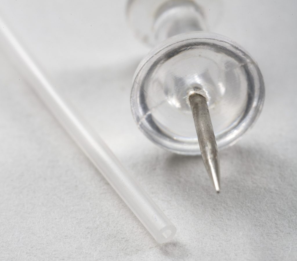 small unreinforced next to a thumb tack for size comparison