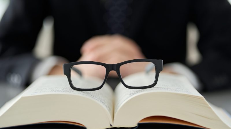 open book with black glasses sitting on the pages