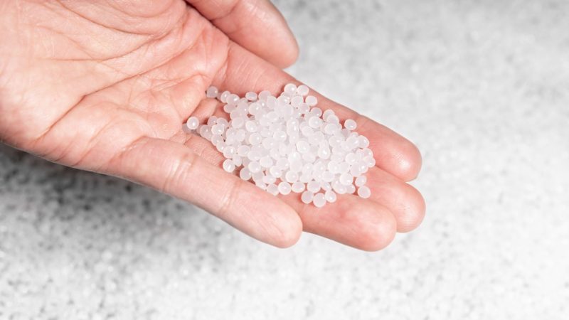 hand holding clear plastic compound pellets